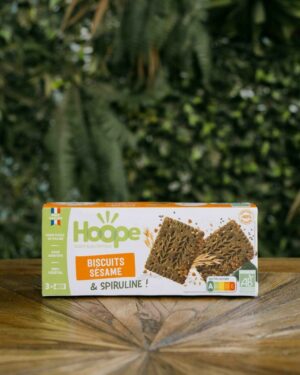 un paquet de biscuit encas sésame posé sur une table en bois avec un fond de mur végétal