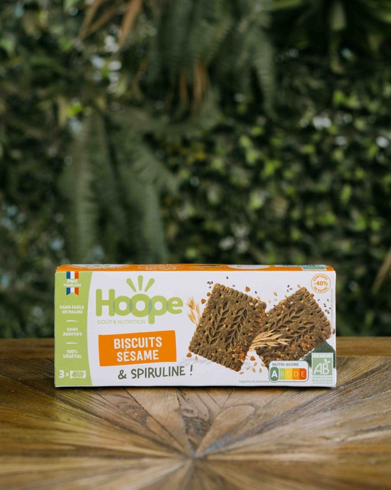 un paquet de biscuit encas sésame posé sur une table en bois avec un fond de mur végétal