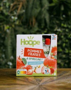 un paquet de compte pommes fraises posé sur une table en bois avec un fond de mur végétal