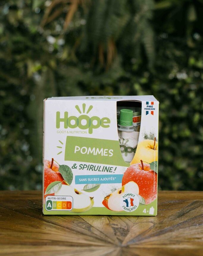 un paquet de compote pommes posé sur une table en bois avec un fond de mur végétal