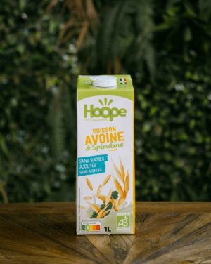 une boisson végétale avoine posée sur une table en bois avec un fond de mur végétal