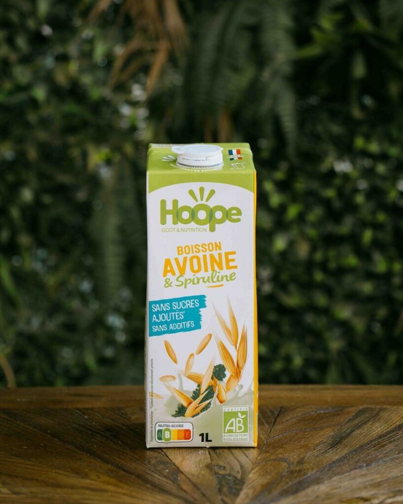 une boisson végétale avoine posée sur une table en bois avec un fond de mur végétal