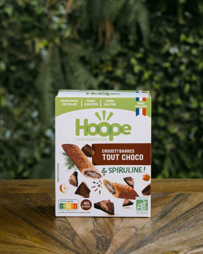 1 paquet de crousti barres tout choco posé sur une table en bois avec un fond de mur végétal