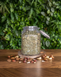 pot en verre avec du muesli 3 noix posé sur une table en bois avec un fond végétal