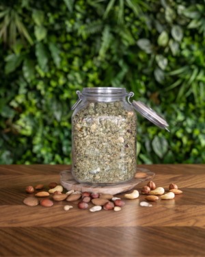 pot en verre avec du muesli 3 noix posé sur une table en bois avec un fond végétal