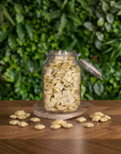 pot en verre avec des céréales fourrées cacao noisette posé sur une table en bois avec un fond végétal