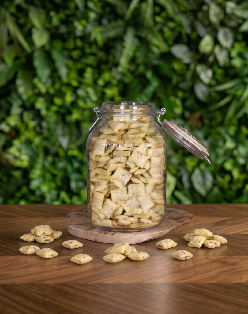 pot en verre avec des céréales fourrées cacao noisette posé sur une table en bois avec un fond végétal