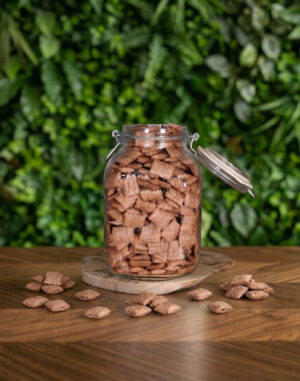 pot en verre avec des céréales fourrées chocolat posé sur une table en bois avec un fond végétal