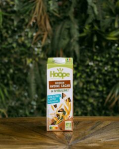 une bouteille de boisson avoine cacao est posée sur une table en bois avec un fond de mur végétal
