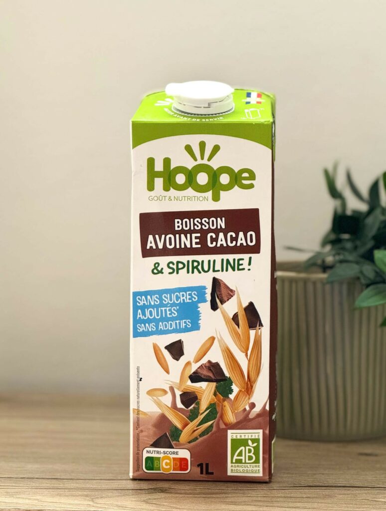 brique de boisson végétale avoine cacao posée sur une table en bois avec une plante en arrière plan