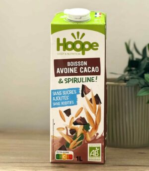 brique de boisson végétale avoine cacao posée sur une table en bois avec une plante en arrière plan