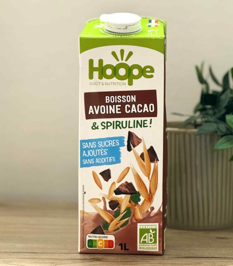 brique de boisson végétale avoine cacao posée sur une table en bois avec une plante en arrière plan