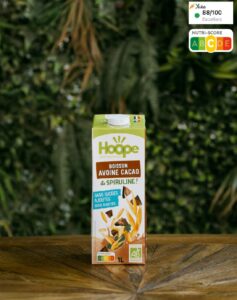 une boisson végétale au lait d'avoine et cacao sur une table en bois avec en arrière plan un mur végétal