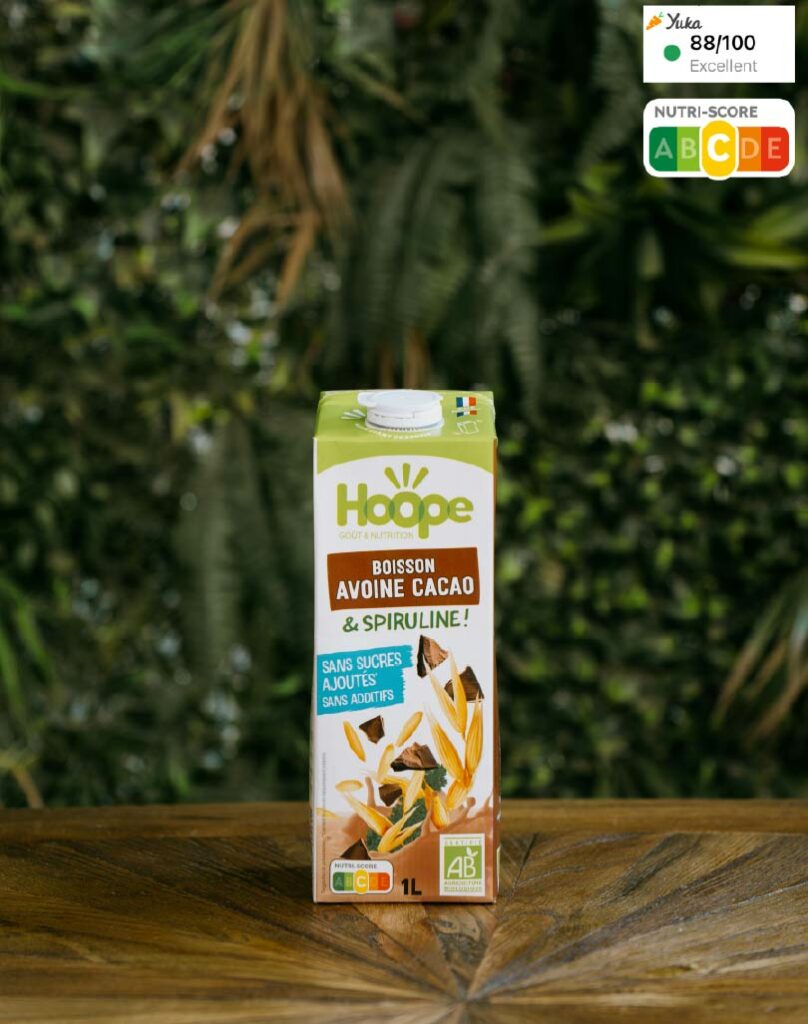une boisson végétale au lait d'avoine et cacao sur une table en bois avec en arrière plan un mur végétal